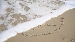 sad face on sand is washed by sea water on beach Stock Footage