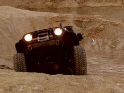 MS ZO Rock crawling jeep with headlights on at dusk climbing up steep incline / Salton City, California, USA  Stock Footage