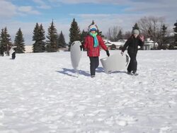 Children walking toward hill to go sledding Stock Footage