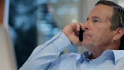 Concerned businessman on smart-phone takes off glasses, reclines in office-chair, and puts glasses back on to scan laptop-computer screen Stock Footage