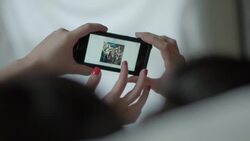 Two young women in hotel bed scroll through photos on smartphone Stock Footage
