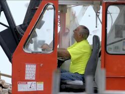 Construction crane operator sitting in cab at the controls of a red crane. Stock Footage