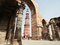 LS Tower Qutub Minar and tourists through archway / Delhi, Punjab, India Stock Footage