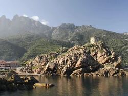 WS View of Village and genovese tower at rocky coast, UNESCO world heritage / Gulf of Porto, Corsica, France Stock Footage