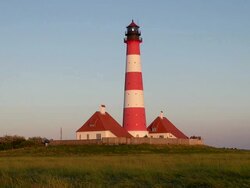 WS View of Westerhever lighthouse from grass field at sunset, North Frisian Wadden Sea / Westerhever, Schleswig Holstein, Germany Stock Footage