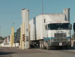 Semi-trucks drive through x-ray inspection Stock Footage