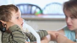 A mother comforts her little boy as he uses a nebulizer to inhale medicine. Stock Footage