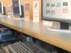CU PAN little boy in public library sits at computer with keyboard and clicks on mouse to access menu on monitor screen designed for children / Rancho Mirage, California, USA Stock Footage