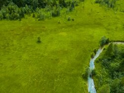 Aerial flight over blue stream flowing through meadows Stock Footage