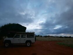 MS T/L Shot of Breeze blows against rooftent on ATV as sunrises through streaming cloudscape with dark and light cloud, blue sky behind / Kalahari, Windhoek, Namibia Stock Footage