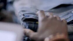 Young employee with tablet counts pants on shelf in modern clothing store Stock Footage