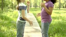 MS, TU, USA, New York State, Bedford Hills, two girls (6-8 years) playing clapping game, standing on boardwalk, side view Stock Footage