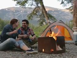 Young couple roasting marshmallows at campfire outside tent Stock Footage