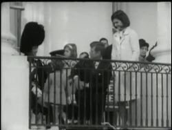 The children of President and Mrs. John F. Kennedy greet a visiting official on a White House balcony. News Clip