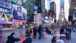 Customers sit down to eat at small tables underneath the neon lights and billboards of Times Square, New York. Stock Footage
