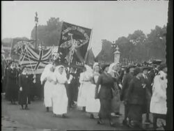 Suffragettes march with banners and a British flag. News Clip
