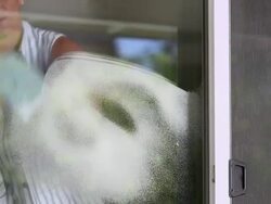 MS PAN TU TD Woman spraying glass cleaner foam onto glass door and wipes  / Rancho Mirage, California, United States Stock Footage