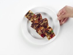 CU Woman hand entering setting down round white plate with slices of holiday, Christmas fruit cake / Omaha, Nebraska, United States Stock Footage