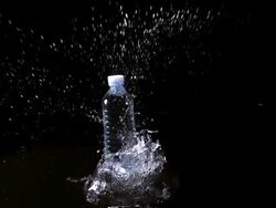 MS SLO MO Shot of Plastic bottle of water falling and splashing against black background / Calvados, Normandy, france Stock Footage