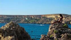 Beautiful girl sunning on a high cliff by the sea Stock Footage