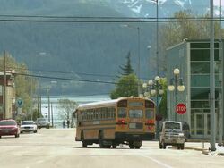 "Yellow school bus pulls out from stop and turns right at intersection of Adams Street and 4th Avenue, shot from corner of Adams Street and 3rd Avenue, Seward, Kenai Peninsula, Alaska." Stock Footage