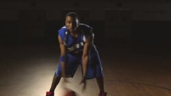 A male basketball player dribbles a basketball between his legs on a gym court. Stock Footage