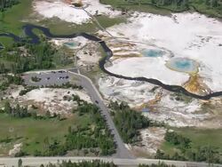 MS AERIAL Shot of hot water fountain holes with car parking area with river stream at Emerald Pool / Wyoming, United States Stock Footage