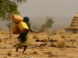 WS, PAN, Rear view of three women carrying containers with water towards village, Niamey, Niger Stock Footage