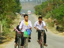 MS SLO MO Shot of group of boys in white shirts riding on bicycles / Road from Luang Prabang to Nong Khio, Luang Prabang, Laos Stock Footage