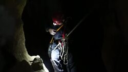 speleology explorer in a cave examining and securing a bolt on a rock 1 Stock Footage