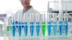 Scientist writing on clipboard behind test tube rack Stock Footage