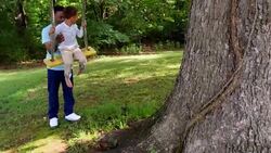 MS PAN Smiling young boy being pushed on swing by father in backyard Stock Footage