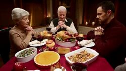 Grandmother saying grace at the Thanksgiving table with her family Stock Footage