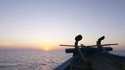 Boat travelling towards setting sun at sea News Clip