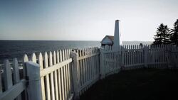 Motion shot of white fence and chapel next to the Permaquid Point Lighthouse in Maine, USA Stock Footage