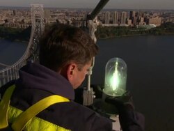 An electrician screws in a light bulb on top of the George Washington Bridge. Stock Footage