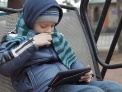 little boy sitting alone on swing with digital tablet Stock Footage