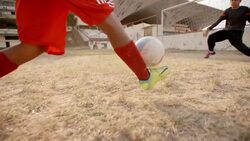 Young soccer player dribbles down field and kicks ball between goalie's hands to score goal Stock Footage