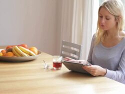 Young female looking at ipad and drinking tea Stock Footage
