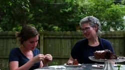 MS Smiling teenage daughter opening birthday gift from mother during celebration in backyard of home Stock Footage