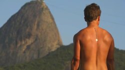 Brazilian man lifts weights on beach with Sugarloaf Mountain towering in distance Stock Footage
