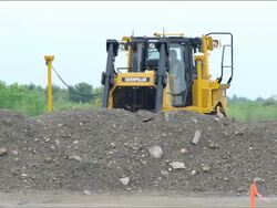 Bulldozer with GPS tracking units working behind a mound of dirt at a construction excavation site Stock Footage
