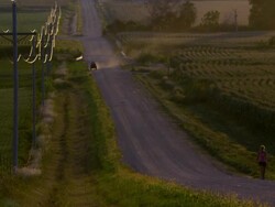 Slow motion static view of woman walking up dirt road. Stock Footage