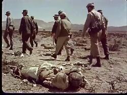 1950s MONTAGE MS Soldiers walking by and looking back at dummy soldier lying in desert / WS soldiers walking by and looking over at small fire in foreground at Camp Desert Rock at Nevada Test Site / Nye County, Nevada, USA Stock Footage