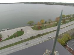 High Angle pan-right tilt-down - Traffic travels on a freeway near a shoreline and high rise buildings. / Wisconsin, USA Stock Footage