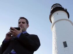MS Man standing near lighthouse while typing on mobile device / Portland, ME, United States Stock Footage