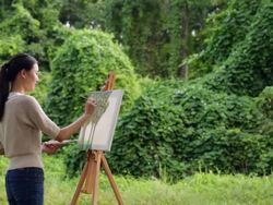 MS Woman painting on an easel in a forest. Stock Footage