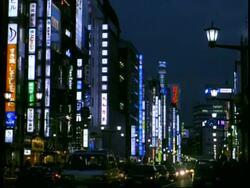 MWA traffic moving through city street, surrounded by High rise buildings and neon signs, at night, Ginza, Tokyo, Japan Stock Footage