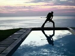 WS Male poi dancer performing in front of pool with reflection of his silhouette in pool at sunrise / Montezuma, Costa Rica Stock Footage