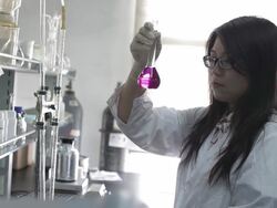 Asian female scientist looking at beaker of liquid Stock Footage